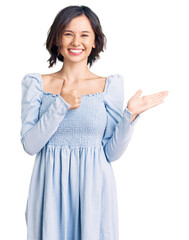 Young beautiful girl wearing casual clothes showing palm hand and doing ok gesture with thumbs up, smiling happy and cheerful