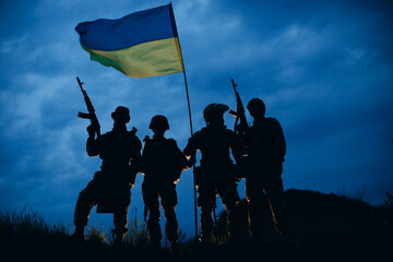 A group of armed Ukrainian warriors with a national flag in the evening