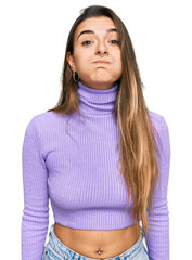 Young hispanic woman wearing casual clothes puffing cheeks with funny face. mouth inflated with air, crazy expression. - obrazy, fototapety, plakaty