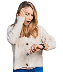 Young blonde woman wearing casual clothes looking at the watch time worried, afraid of getting late