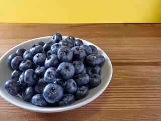 Freshly picked blueberries in a white vintage ceramic bowl. Selective focus, Free text space.