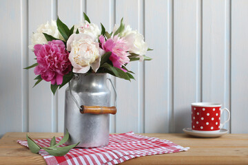 Obraz na płótnie Canvas A bouquet of peonies in an aluminum can on a wooden table.