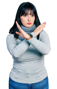 Young hispanic plus size woman wearing winter scarf rejection expression crossing arms and palms doing negative sign, angry face