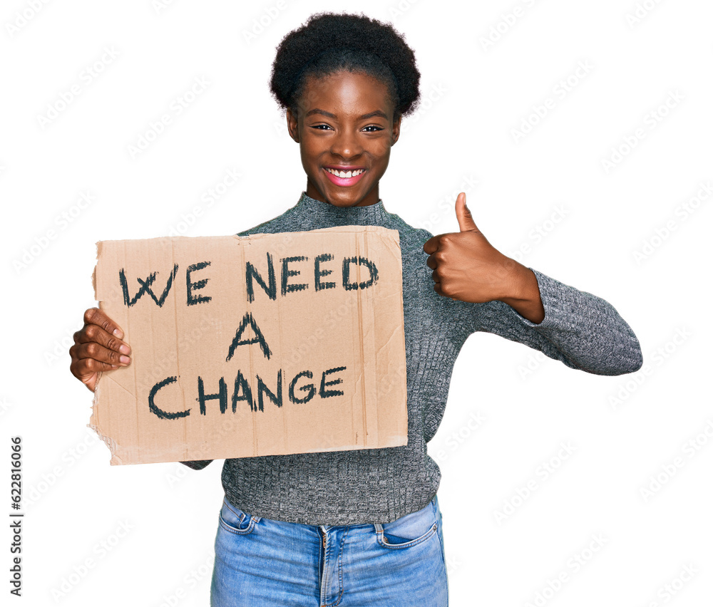 Sticker Young african american girl holding we need a change banner smiling happy and positive, thumb up doing excellent and approval sign