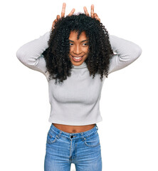 Young african american girl wearing casual clothes posing funny and crazy with fingers on head as...