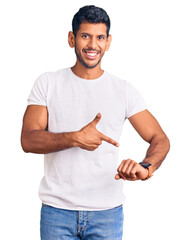 Young latin man wearing casual clothes in hurry pointing to watch time, impatience, upset and angry...