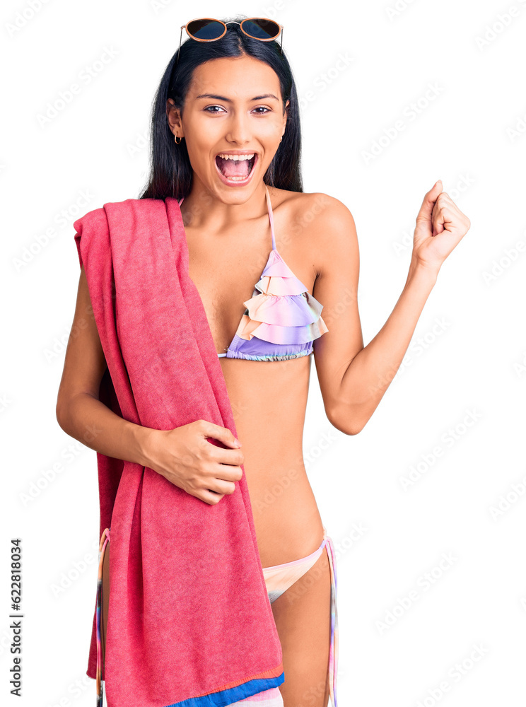 Poster young beautiful latin girl wearing bikini and sunglasses screaming proud, celebrating victory and su