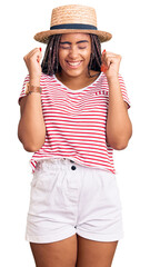 Young african american woman with braids wearing summer hat excited for success with arms raised and eyes closed celebrating victory smiling. winner concept.