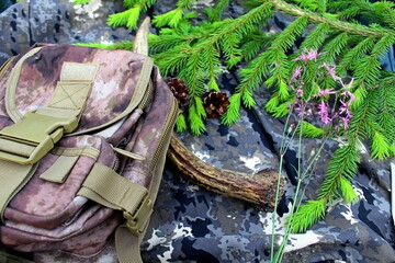Equipment for outdoor travel on camouflage fabric with branches of coniferous trees