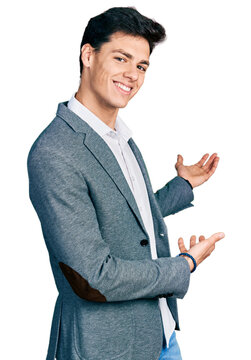 Young hispanic man wearing business clothes inviting to enter smiling natural with open hand