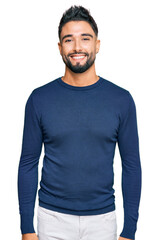 Young man with beard wearing casual blue winter sweater looking positive and happy standing and smiling with a confident smile showing teeth