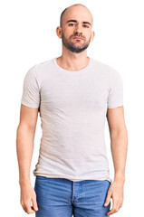 Young handsome man wearing casual t shirt relaxed with serious expression on face. simple and natural looking at the camera.