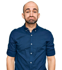 Young hispanic man wearing casual clothes puffing cheeks with funny face. mouth inflated with air, crazy expression. - obrazy, fototapety, plakaty