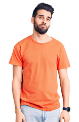 Young handsome man with beard wearing casual t-shirt looking sleepy and tired, exhausted for fatigue and hangover, lazy eyes in the morning.