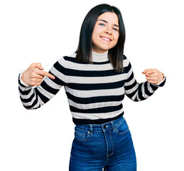 Young brunette woman with blue eyes wearing casual striped sweater looking confident with smile on face, pointing oneself with fingers proud and happy.