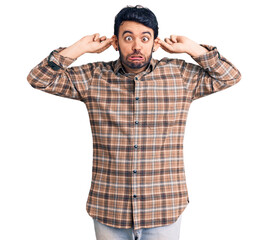 Young hispanic man wearing casual clothes smiling pulling ears with fingers, funny gesture....