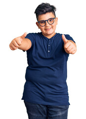 Little boy kid wearing casual clothes and glasses approving doing positive gesture with hand, thumbs up smiling and happy for success. winner gesture.