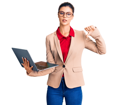 Young beautiful woman holding laptop with angry face, negative sign showing dislike with thumbs down, rejection concept