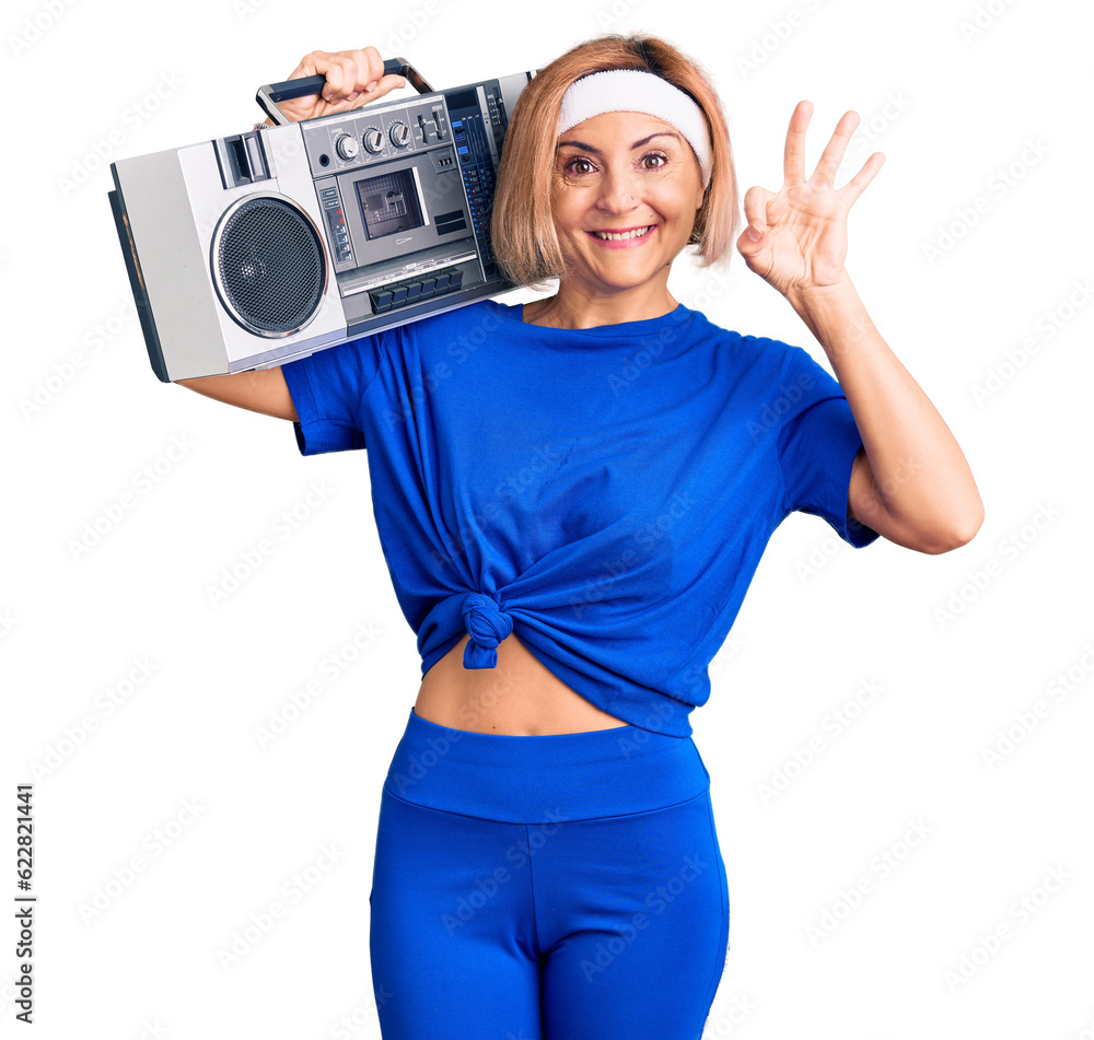 Sticker young blonde woman wearing sportswear holding boombox, listening to music doing ok sign with fingers