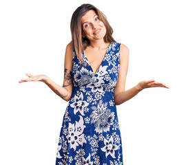 Beautiful caucasian woman wearing summer dress clueless and confused expression with arms and hands...