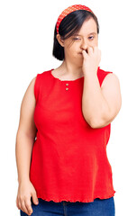 Brunette woman with down syndrome wearing casual clothes looking stressed and nervous with hands on mouth biting nails. anxiety problem.
