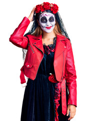 Woman wearing day of the dead costume over background confuse and wonder about question. uncertain with doubt, thinking with hand on head. pensive concept.