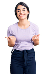 Brunette teenager girl wearing casual clothes very happy and excited doing winner gesture with arms raised, smiling and screaming for success. celebration concept.