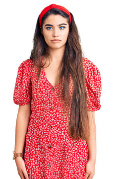 Brunette teenager girl wearing summer dress relaxed with serious expression on face. simple and natural looking at the camera.