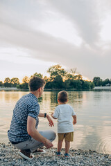 happy family dad and son throw stones into the lake on a walk