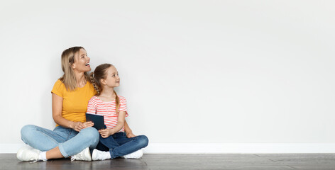 Nice Offer. Mom And Little Daughter Holding Digital Tablet And Looking Aside