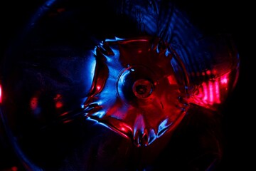 Base geométrica de una botella plástica de jugo iluminada con luz  azul y rojo, forma una figura hexagonal en el espacio, presenta un  original y bonito diseño abstracto con fondo oscuro