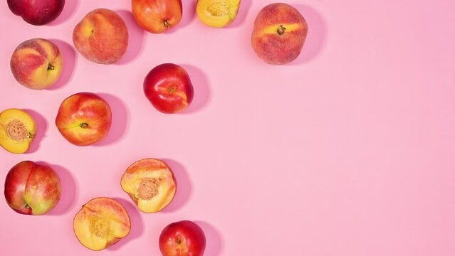 Summer background with fresh peach fruits move on pastel pink background. Flat lay. Stop motion