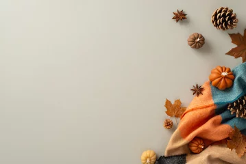  Embrace the comfort of home in fall with this top view image. Cozy patchy plaid and autumnal attributes - pumpkin candles, pinecones and maple leaves create cozy setting for copyspace on grey backdrop © ActionGP