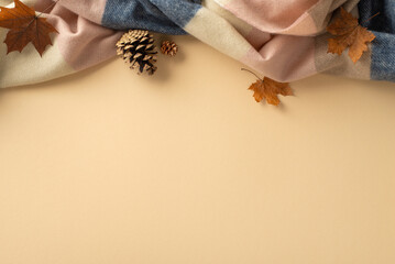 Embrace the warmth of autumn at home: Top view picture with a cashmere patchy plaid with maple foliage and pinecones on beige isolated background. Perfect for text or advertising purposes
