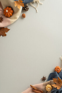 Autumnal treasures on display: Above vertical view picture with cinnamon sticks, Chinese anise, pinecones, maple leaves and pumpkin-shaped candles on grey isolated background, perfect for showcasing