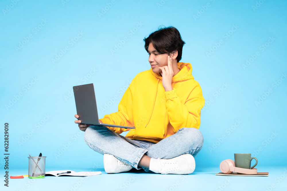 Wall mural japanese student guy using laptop making video call, blue background