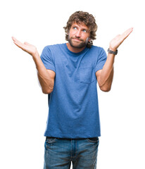 Fototapeta premium Handsome hispanic model man over isolated background clueless and confused expression with arms and hands raised. Doubt concept.
