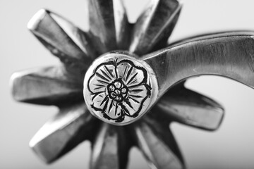 Western spur rowel with flower engraved on metal closeup in black and white. - obrazy, fototapety, plakaty