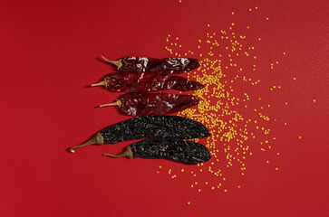 Dried Chilis and Seeds on Red background, Pasilla and Guajillo mexican spice flat lay