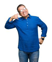 Fototapeta premium Middle age arab man wearing glasses over isolated background smiling doing phone gesture with hand and fingers like talking on the telephone. Communicating concepts.