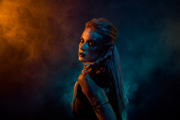 Fototapeta premium Profile photo of terrifying valkyrie pagan woman scary glance orange blue color lights isolated on dark background