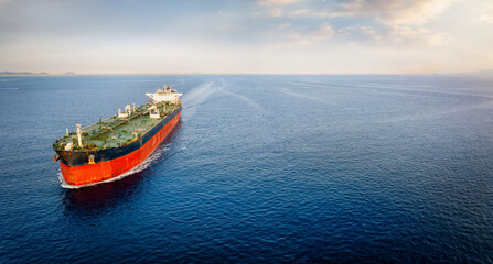 Aerial view of a large crude oil tanker traveling over calm sea during sunset with copy space - obrazy, fototapety, plakaty