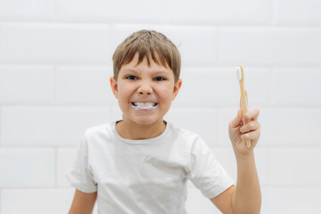 cute 8 years old boy brushing teeth with bamboo tooth brush in bathroom. Image with selective focus