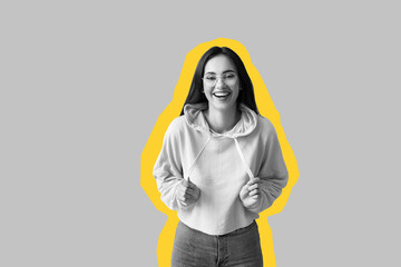 Happy young woman in stylish hoodie on grey background