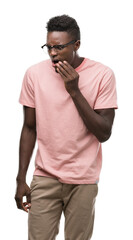 Young african american man wearing pink t-shirt touching mouth with hand with painful expression because of toothache or dental illness on teeth. Dentist concept.