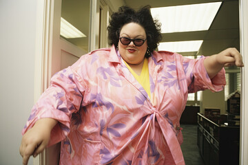 A plump plus size woman in a pink shirt and sunglasses standing in a hallway. Generative AI.