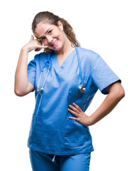 Young brunette doctor girl wearing nurse or surgeon uniform over isolated background smiling doing phone gesture with hand and fingers like talking on the telephone. Communicating concepts.