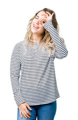 Beautiful young blonde woman wearing stripes sweater over isolated background doing ok gesture with hand smiling, eye looking through fingers with happy face.