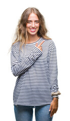 Beautiful young blonde woman wearing stripes sweater over isolated background cheerful with a smile of face pointing with hand and finger up to the side with happy and natural expression on face