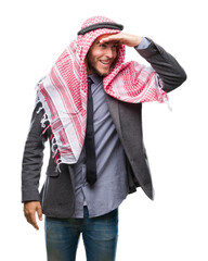 Young handsome arabian man with long hair wearing keffiyeh over isolated background very happy and smiling looking far away with hand over head. Searching concept.